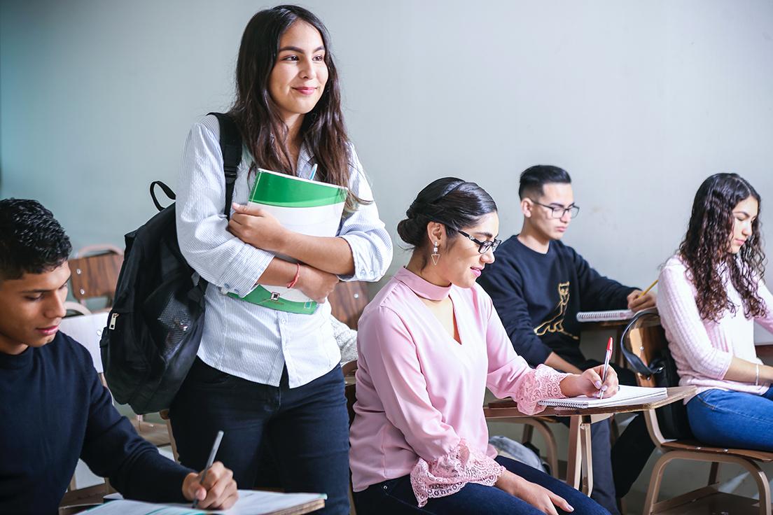 学生们在课堂上，一个拿着书包和笔记本站着